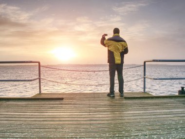 İskele inşaat ve fotoğraf sabah deniz adamı. Yumuşak su seviyesinden akıllı telefon ile turizm