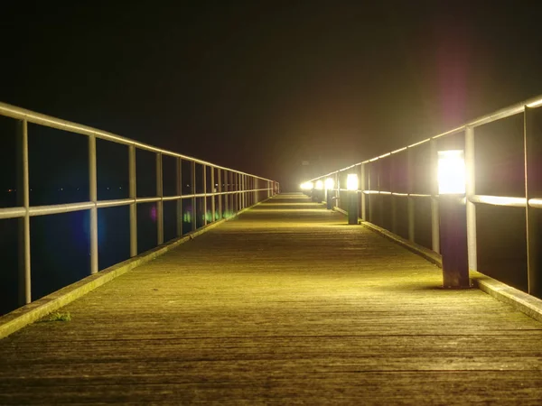 Wooden terrace mole or pier early morning. View of wooden bridge above smooth ocean. Perspective of wooden pier in dock