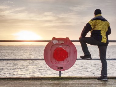 Mor daybreak limanda trekking takım elbiseli bir adam. Turistik köstebek deniz üzerinde ahşap zemin ıslak.
