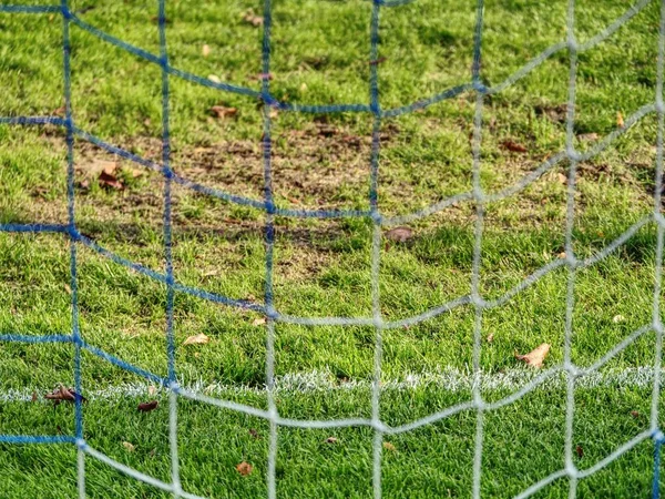 Soccer or football corner lines through safety net. View from behind the tribune net with blurred stadium and field pitch