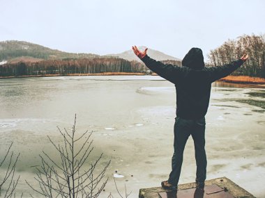Gölet soğuk yağmurlu bir gün. Islak adam riverside tarafından ayakta 