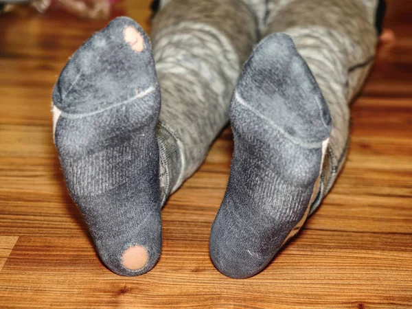 Kid wearing dirty sweaty socks with holes in heel. Pink skin in soks hole