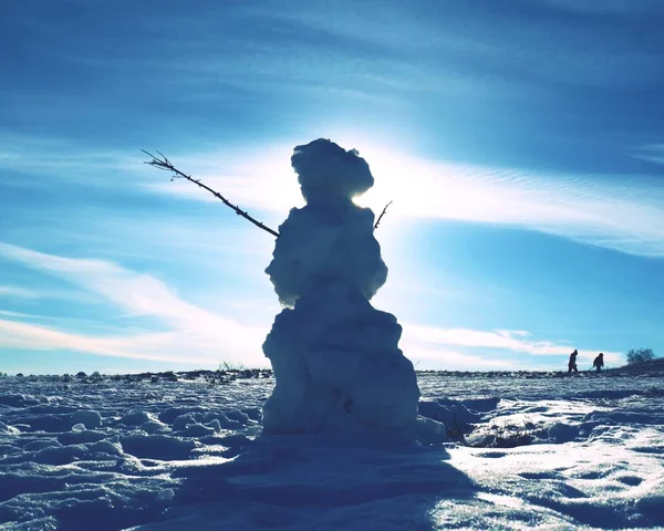 真正冰冷的雪人站在冬日的风景中 温泉的阳光和一些人走在地平线上 — 图库照片