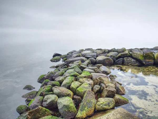 El rompeolas en el agua tranquila del mar de tarde . — Foto de Stock