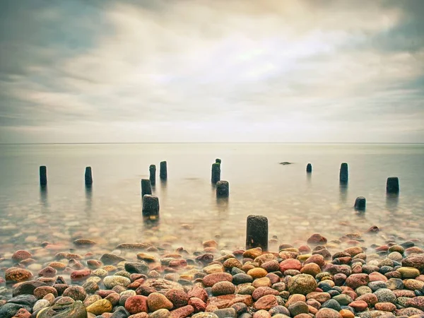 El rompeolas en el agua tranquila del mar de tarde . — Foto de Stock