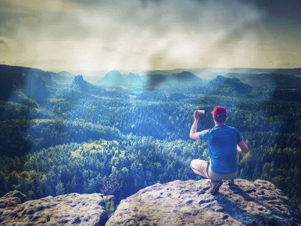 Filtered.  Fearless man in sportswear is sitting on cliff edge. — Stock Photo, Image