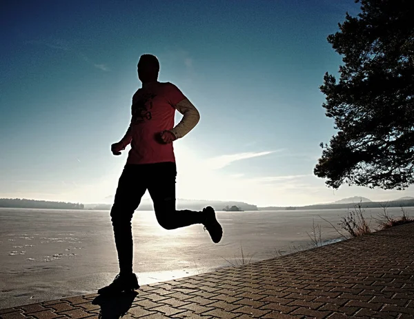 Hombre soltero corriendo entrenamiento, ejercicio para correr cerca del lago congelado — Foto de Stock