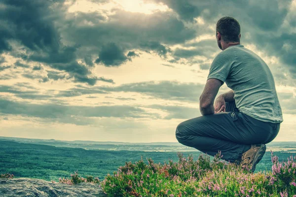 Tall man sits on a hillside in heather bush — Stock Photo, Image