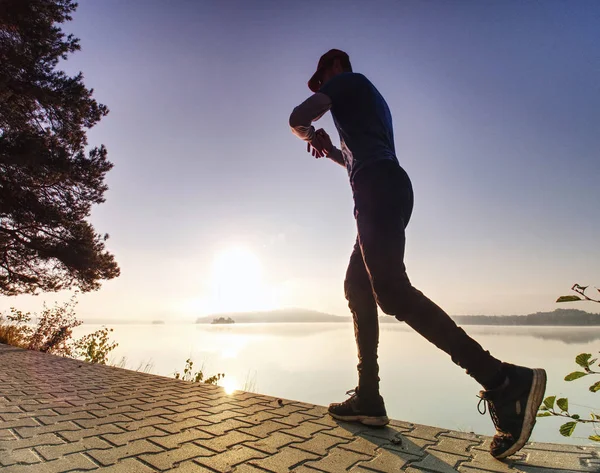 Man running looking at heart rate monitor watch.