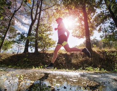 Koşan adam ve parkta tek başına excersising. Güneşin arkasında 