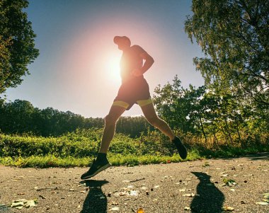 İnce gövde adam yolu düşen yapraklar ile çalışır. Sıcak gün 
