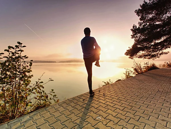 Sport actif homme coureur étirement corps sur la chaussée côté lac , — Photo