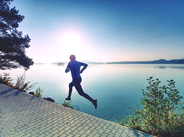 Correr regularmente en el lago. Hombre corredor corriendo al aire libre en la naturaleza escénica — Foto de Stock