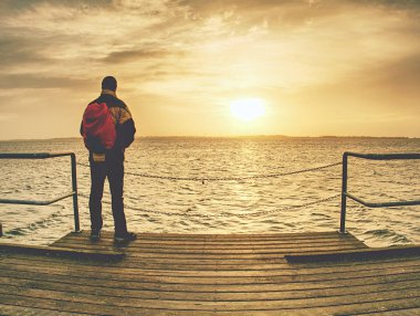 Backpacker turist denizde eski tahta köprüde duran. 