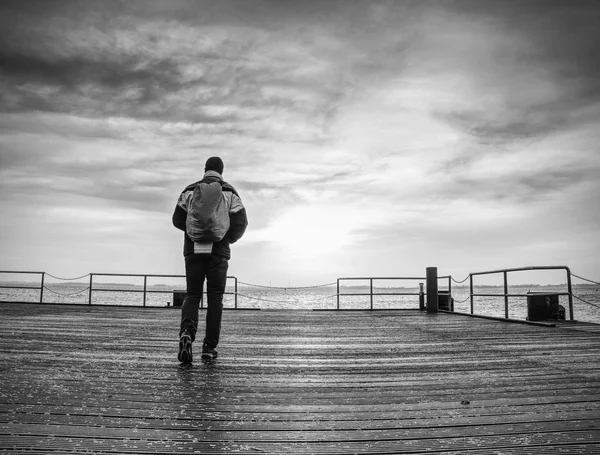 Backpacker tourist standing at sea on old wooden bridge. — Stock Photo, Image