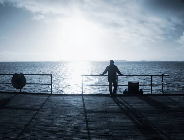 L'homme seul reste sur le pont de mer et regarde l'incroyable lever du soleil . — Photo