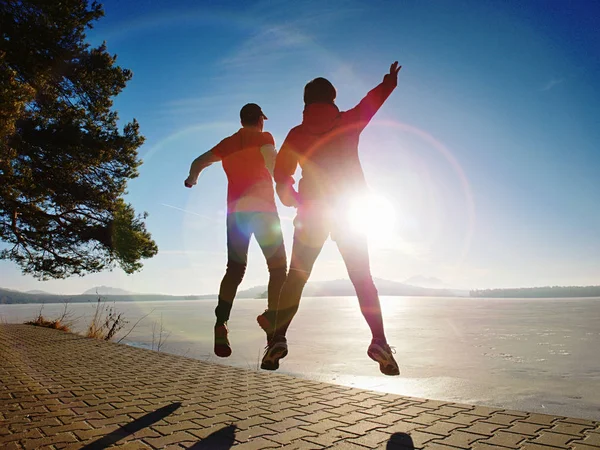 El hombre y la mujer hacen deportes en el lago contra el fuerte sol de la mañana . —  Fotos de Stock