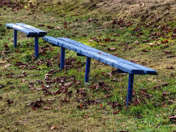 Modrá stará pustá lavička s podzimním listí. — Stock fotografie