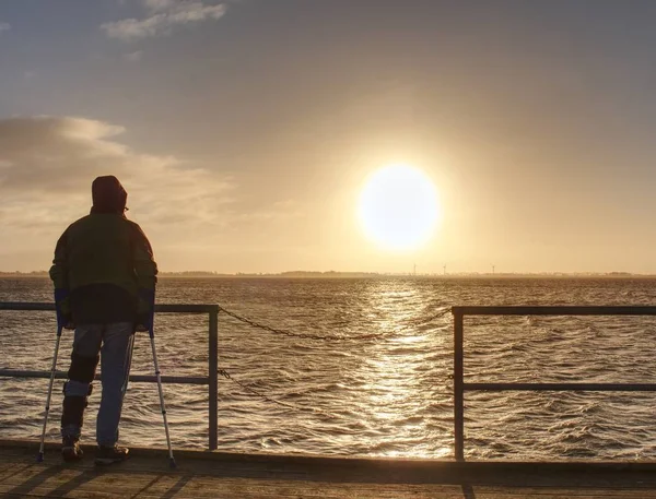 Mann wandert allein und beobachtet Sonnenaufgang über Seebrücke — Stockfoto