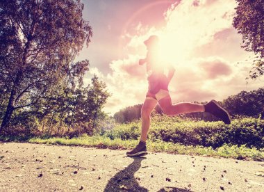 Koşan adam ve parkta tek başına excersising. Güneşin arkasında 