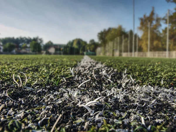Striscia bianca sul campo di calcio verde artificiale. foglie gialle cadute — Foto Stock