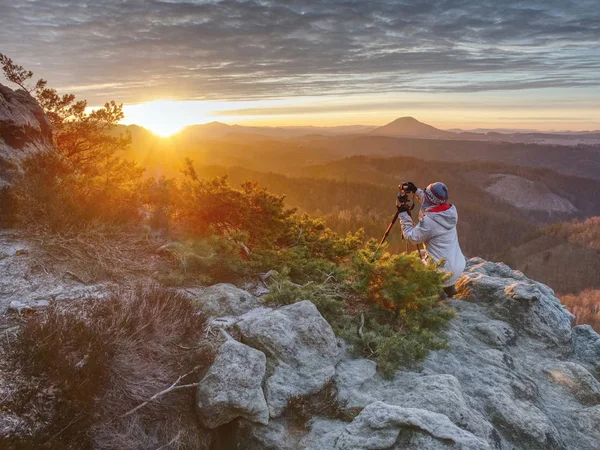 Kvinna vandrare set stativ med kamera på exponerade stenig topp — Stockfoto