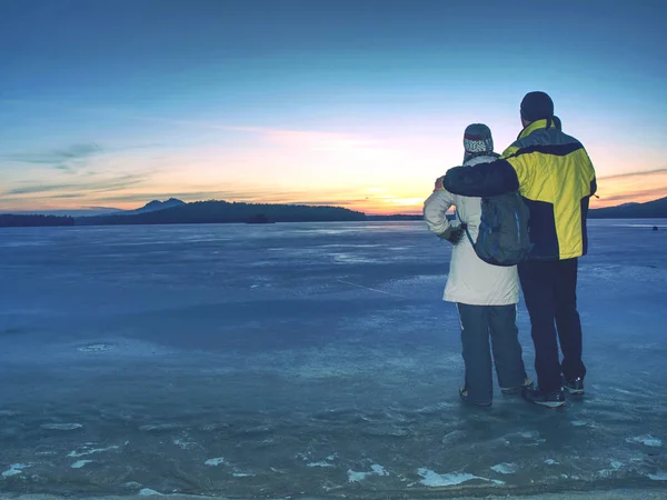 Los amantes se mantienen en hielo en la laguna congelada y observan el sol — Foto de Stock