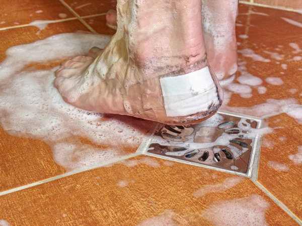 Mujer tomar la ducha con paster en la ampolla del talón — Foto de Stock