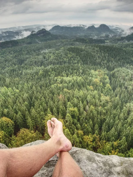 Young man sit down on mountain edge barefoot. — Stock Photo, Image