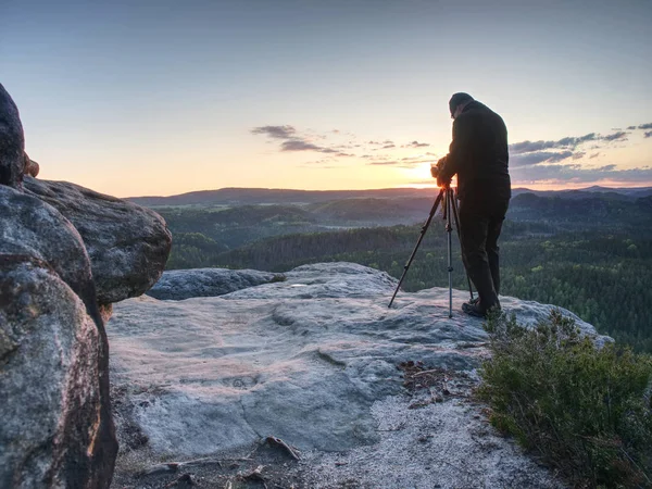 Photographer takes photos with camera on tripod on rock — Stock Photo, Image