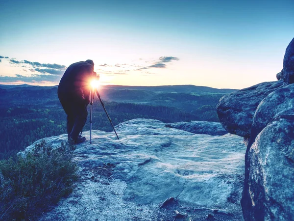 Photographe prend des photos avec appareil photo sur trépied sur roche — Photo