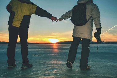 Genç aşık çift kışlık kalın giysiler giyer buzda kalır ve el ele tutuşurlar.