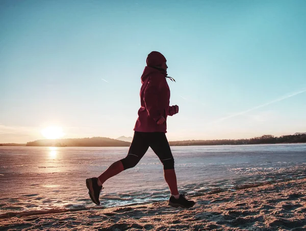 Running sport woman. Female runner jogging at winter bay