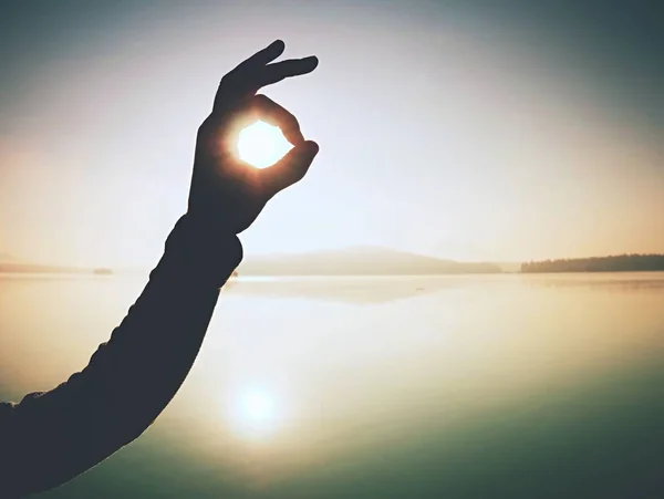 Dedos señalando el marco de la foto en la salida del sol junto al mar. Luz solar en la playa . — Foto de Stock
