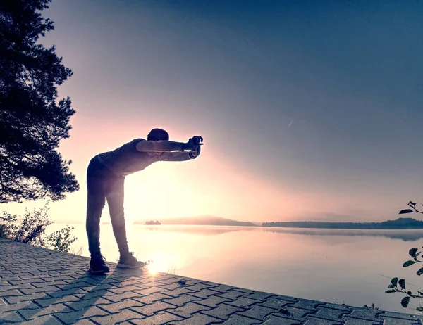 Breve pausa per respirare. Silhouette dell'uomo attivo sulla spiaggia del lago — Foto Stock