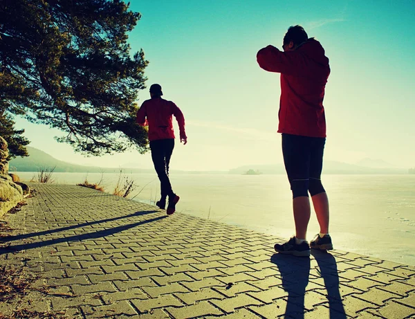 Um homem a correr com a namorada na margem do rio. Colinas com sol quente — Fotografia de Stock