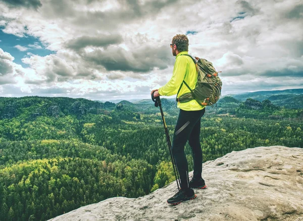 Athlete man tourist hiking mountain trail, walking on rock