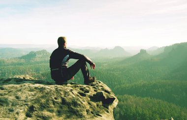 Adam sis arka planda uçurumun kenarına oturur