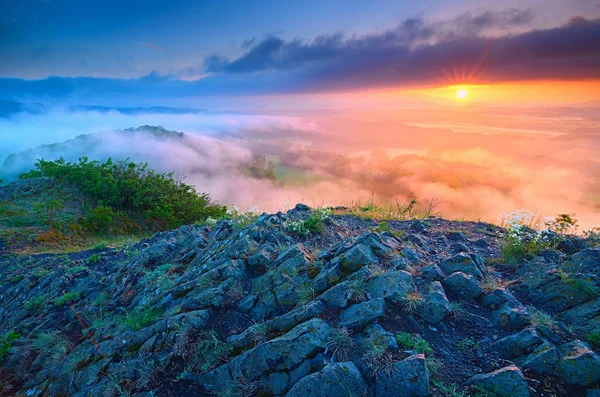 Magic dark basalt poles on peak above misty valley after daybreak. — Stock Photo, Image