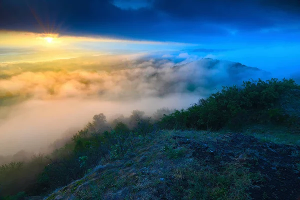 Bâtons de basalte sombres magiques sur le sommet au-dessus de la vallée brumeuse après le lever du jour . — Photo