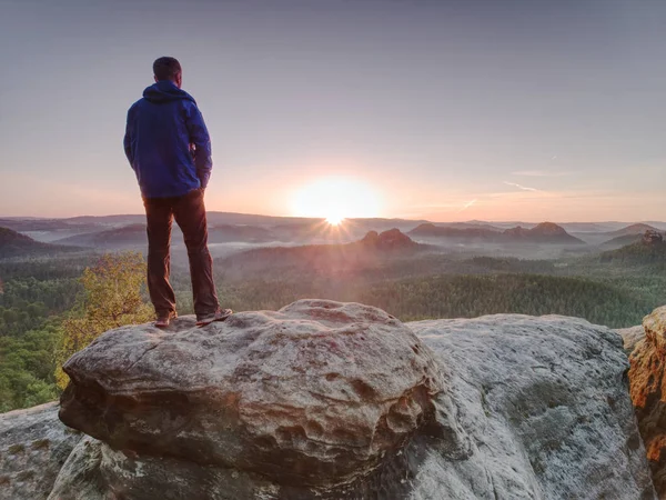 Mann geht über felsigen Gipfel bei aufgehender Sonne. schöner Moment — Stockfoto