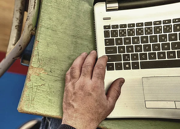 Old hands with wrinkles typing on laptop. Modern old person