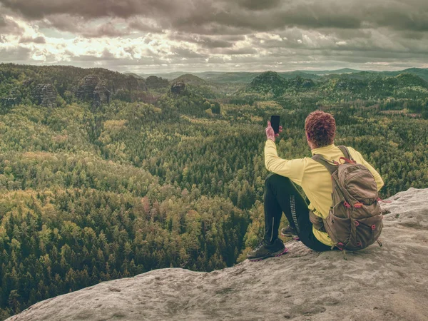 Ginger Man neemt Foto's met Smart Phone op Rocky Peak. — Stockfoto