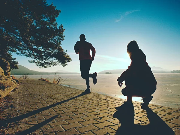 Чоловік і жінка займаються спортом на озері проти сильного ранку Сонце . — стокове фото