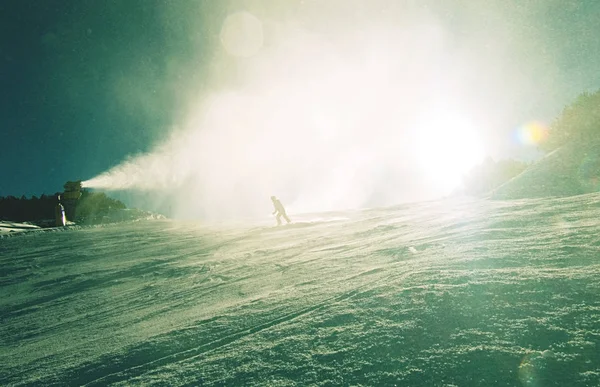 Snowboarders e canhão de neve em ação. Canhão de neve — Fotografia de Stock