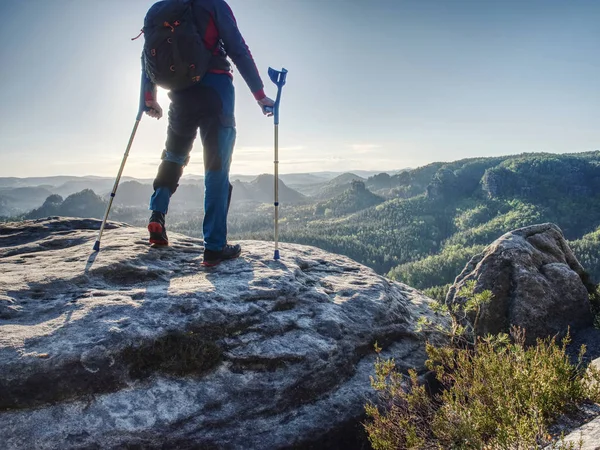 Uomo forte ferito in piedi con le stampelle sulla cima della montagna . — Foto Stock