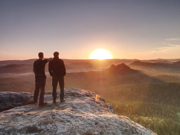 Wandelers en vrienden op Cliff binnen dromerige Daybreak en denken. — Stockfoto