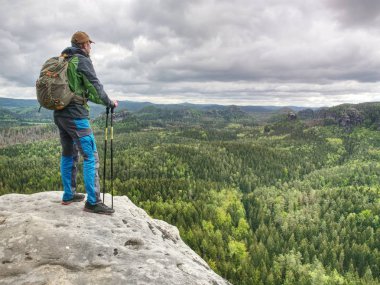 Bir sırt çantası ve koşu ayakkabıları olan adam bir kayanın üstünde duruyor