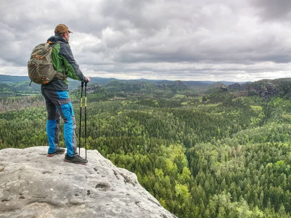 Man met een rugzak en loopschoenen staat op de top van een rots — Stockfoto
