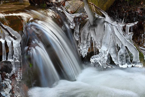 Bevroren cascade van waterval ijzige twijgen en rotsblokken in bevroren schuim — Stockfoto